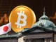 Imagem mostrando uma moeda de Bitcoin dourada ao lado de um edifício governamental japonês com a bandeira do Japão.