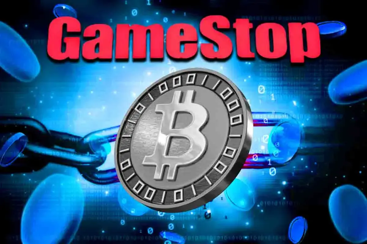 Logo da GameStop em vermelho com moeda de Bitcoin prateada centralizada sobre fundo digital azul com elementos tecnológicos.