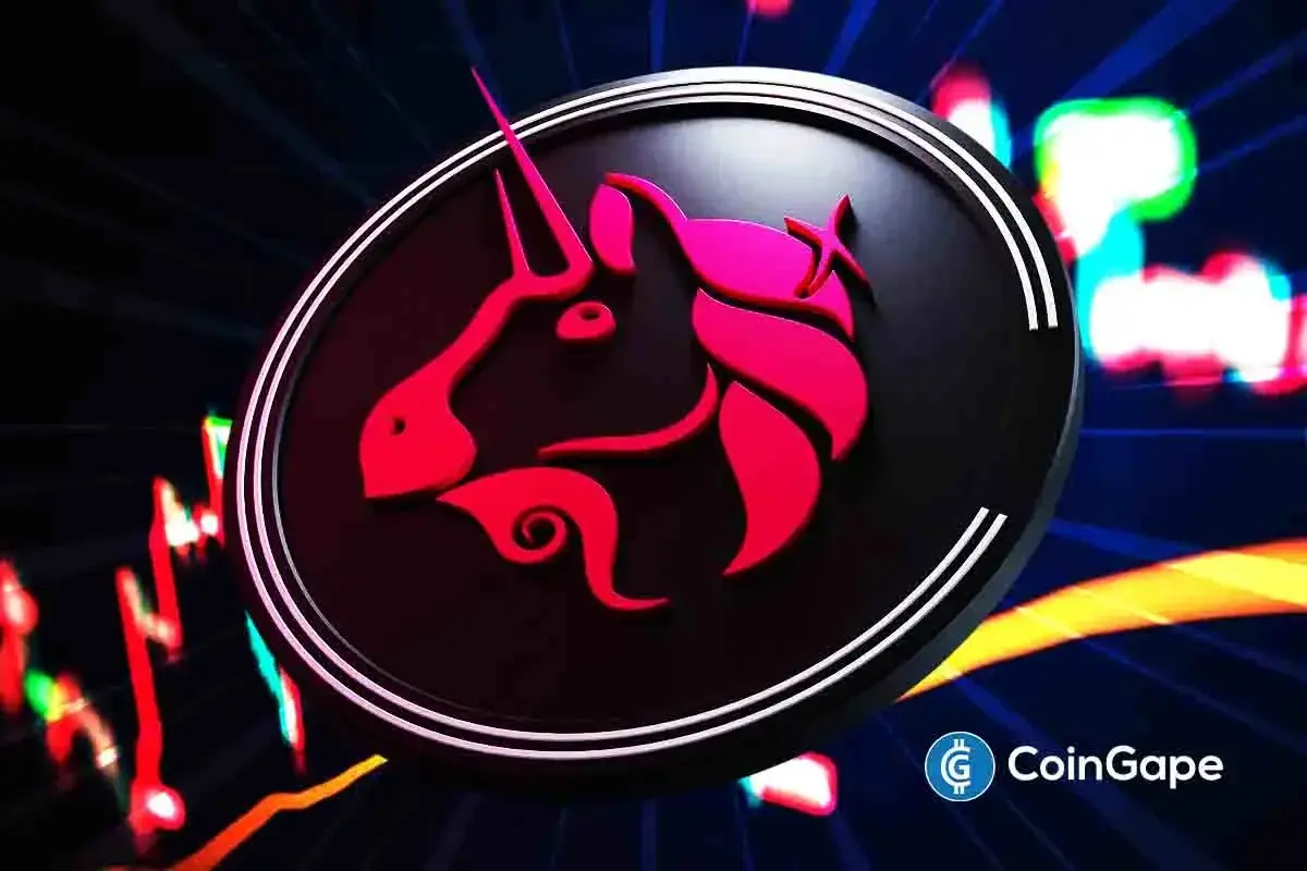 Logotipo do unicórnio Uniswap em vermelho e rosa dentro de uma lupa sobre fundo escuro com luzes coloridas desfocadas.